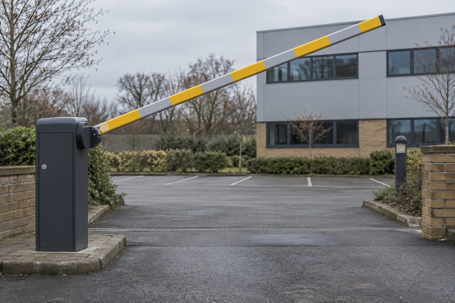 A yellow and grey barrier arm is raised at the entrance to an empty car park.